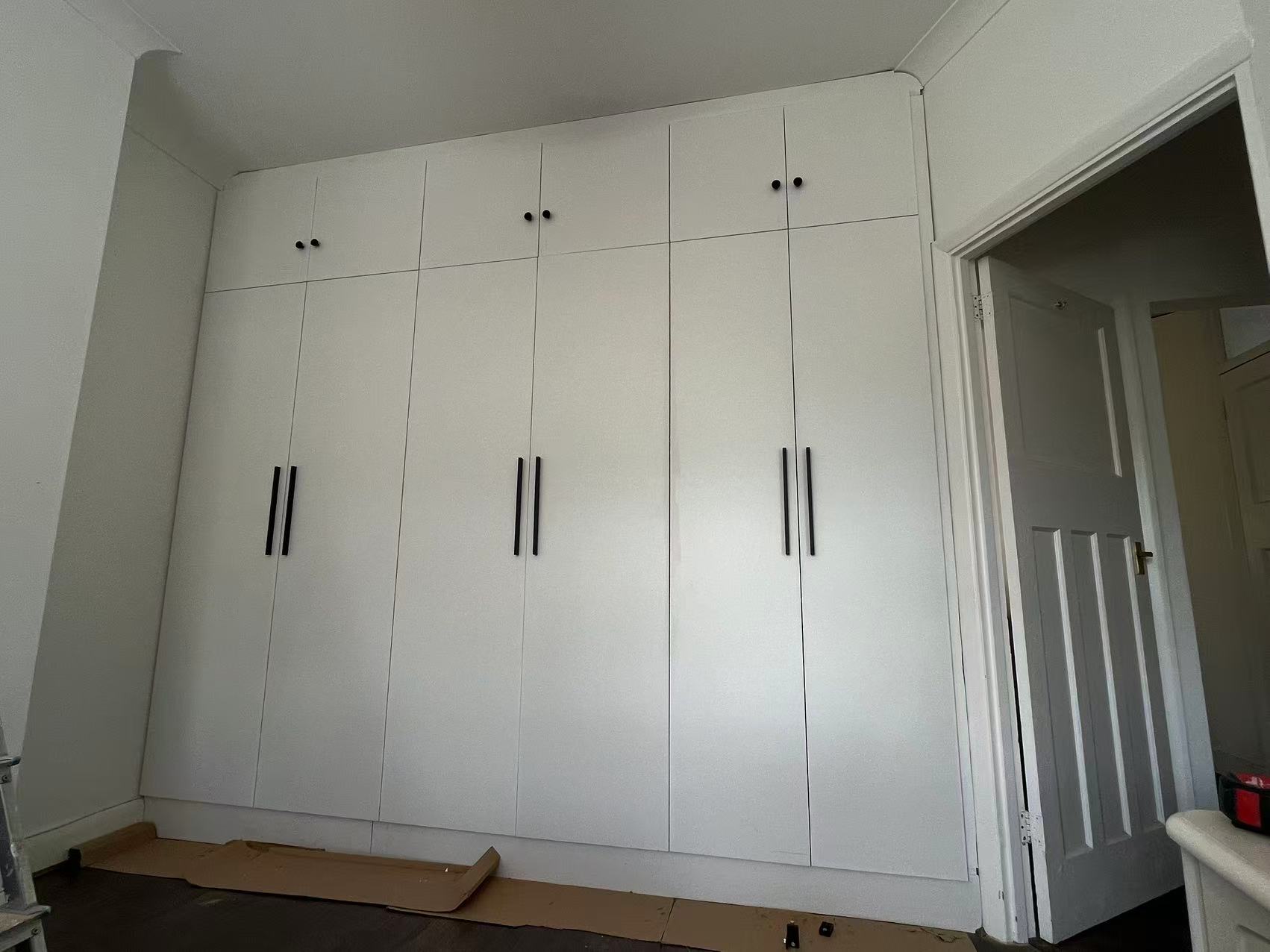 Floor-to-ceiling fitted wardrobes with black bar handles — image 1