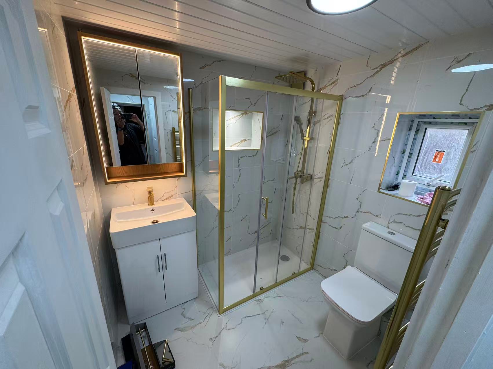 Marble-effect shower room with brushed gold fittings — image 1